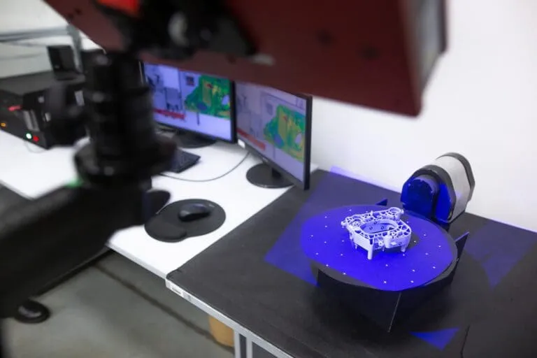 Professional 3D scanner capturing an industrial plastic molding part on a turntable