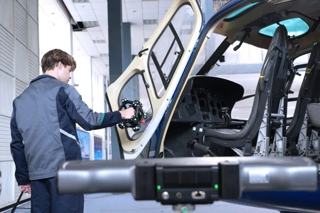 Young man using the Scantech NimbleTrack wireless 3D scanner to scan the inside door of a helicopter