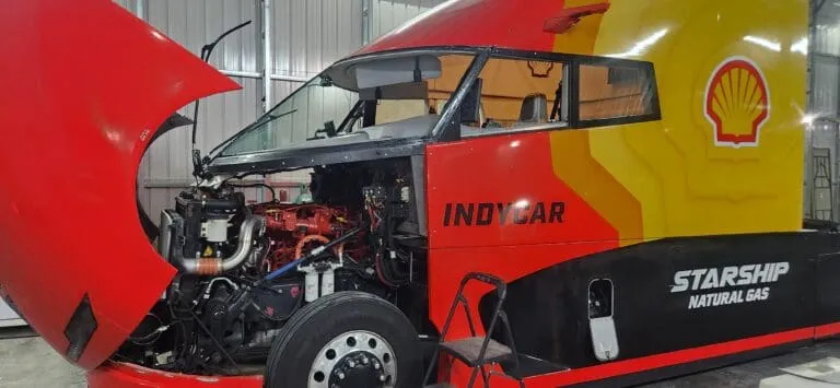 Red and yellow Shell Starship natural gas truck with its hood raised in a workshop