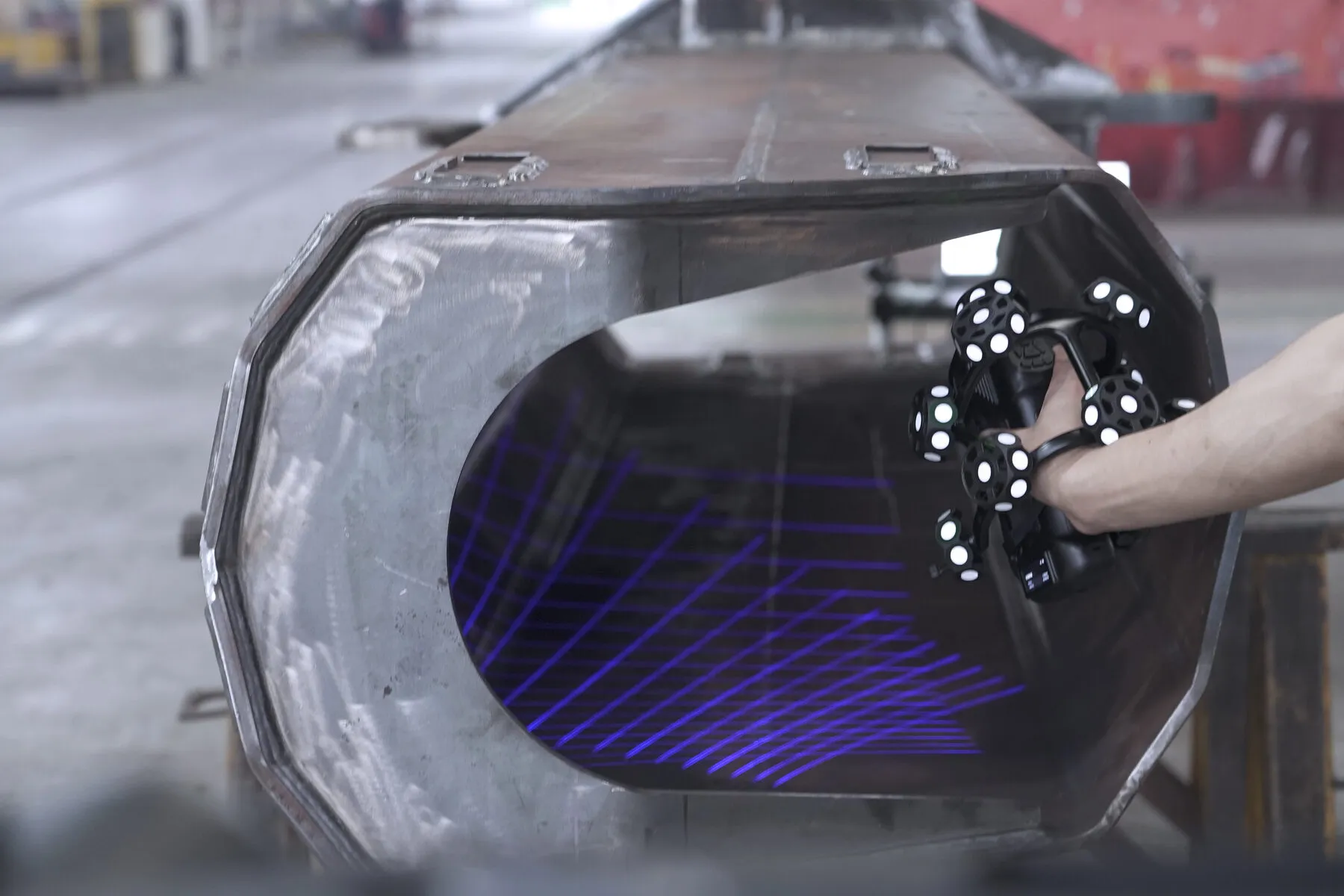 TrackScan GO handheld scanner reaching inside a large cylindrical vessel to capture an internal cavity with blue laser lines