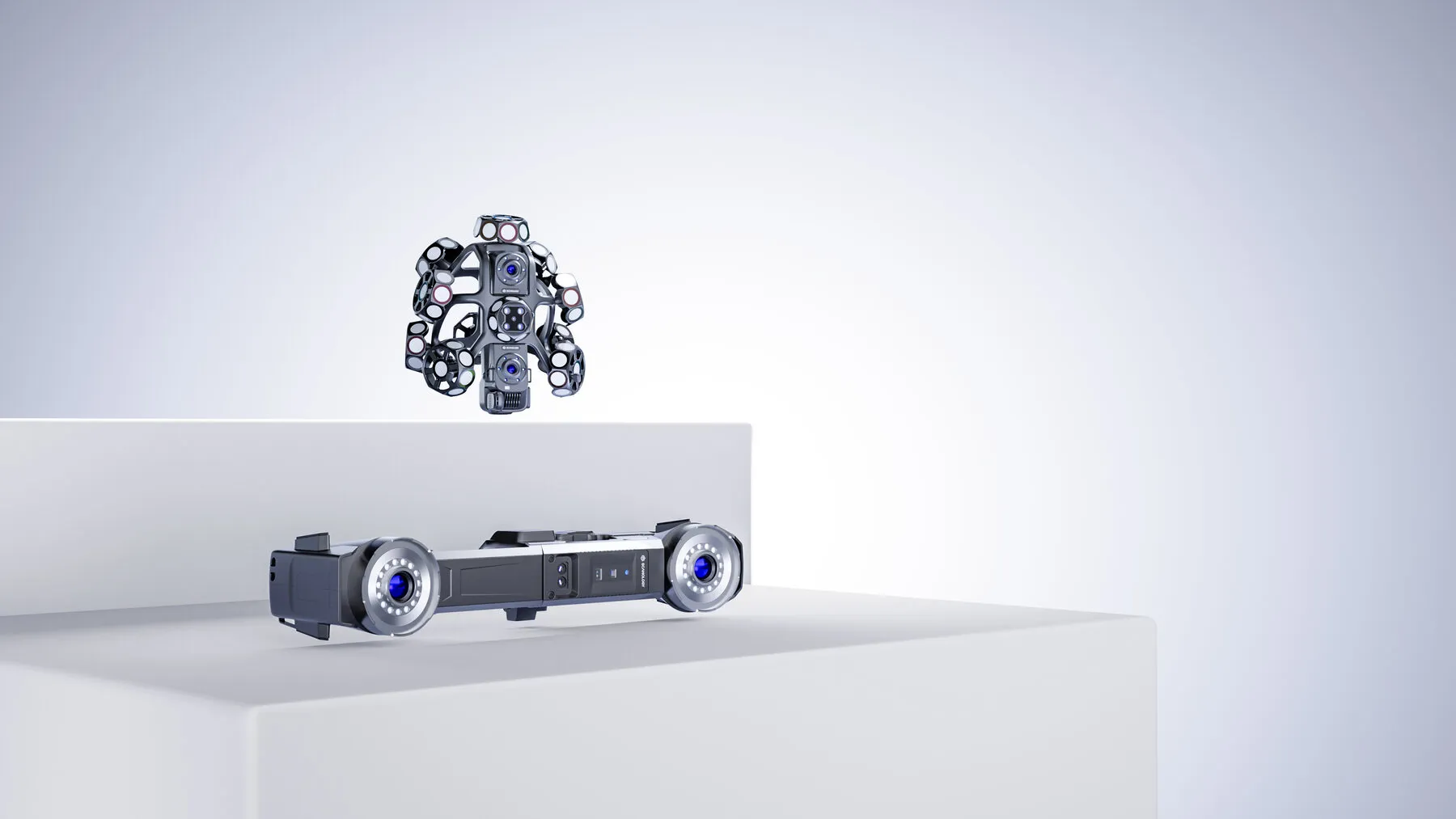Studio render of the TrackScan GO handheld scanner above the i-Tracker resting on a white plinth